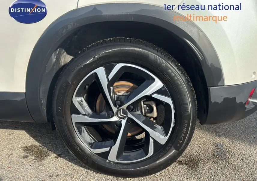 Gros plan sur la roue arrière droite d'un Citroën C5 Aircross blanc nacré avec jante alliage bicolore moderne.