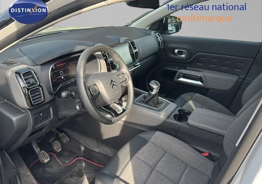 Intérieur du Citroën C5 Aircross blanc nacré 2020, vue côté conducteur, volant, tableau de bord et levier manuel visibles.