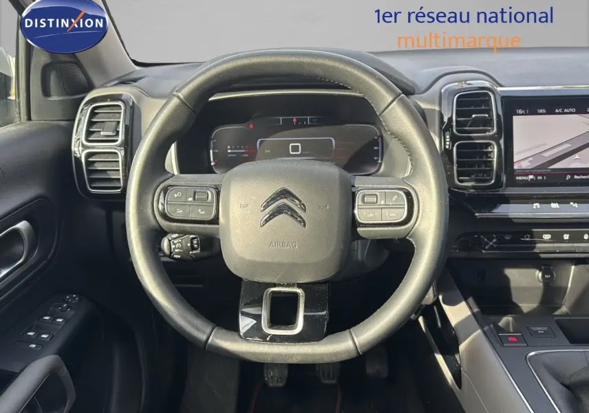 Vue intérieure centrée sur le volant du Citroën C5 Aircross blanc nacré, avec tableau de bord numérique et écran tactile visible.