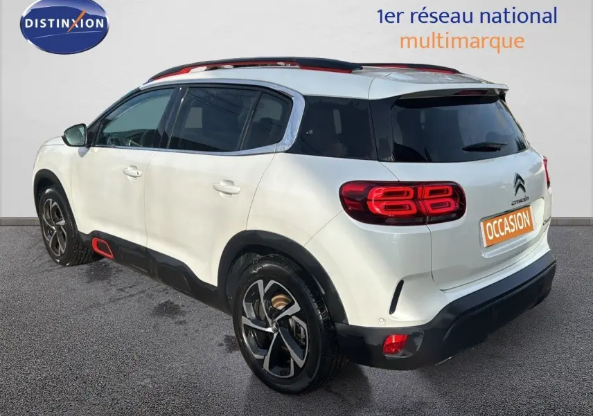 Vue 3/4 arrière droite d'un Citroën C5 Aircross blanc nacré avec détails rouges et jantes noires.