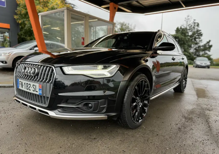 Audi A6 Avant Allroad noire vue en 3/4 avant droit, avec jantes noires et calandre chromée distinctive.