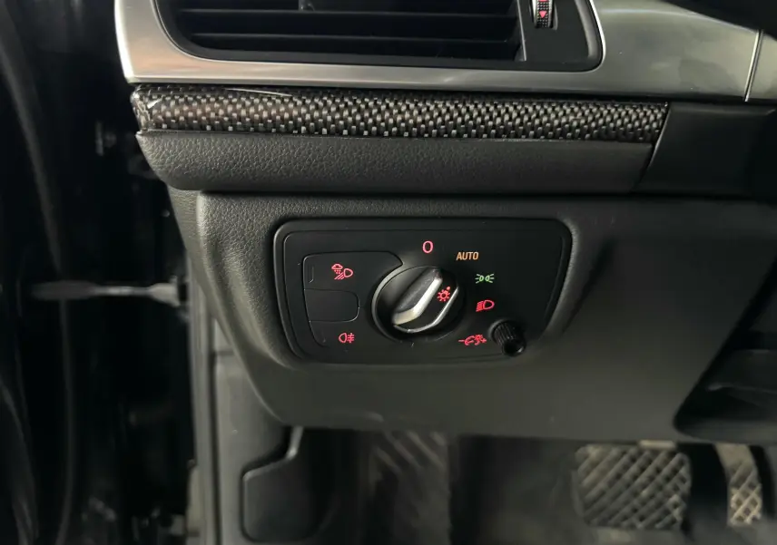 Gros plan sur le panneau de commande des phares avec molette, intérieur noir et insert carbone d'une Audi A6 Avant Allroad 2016.