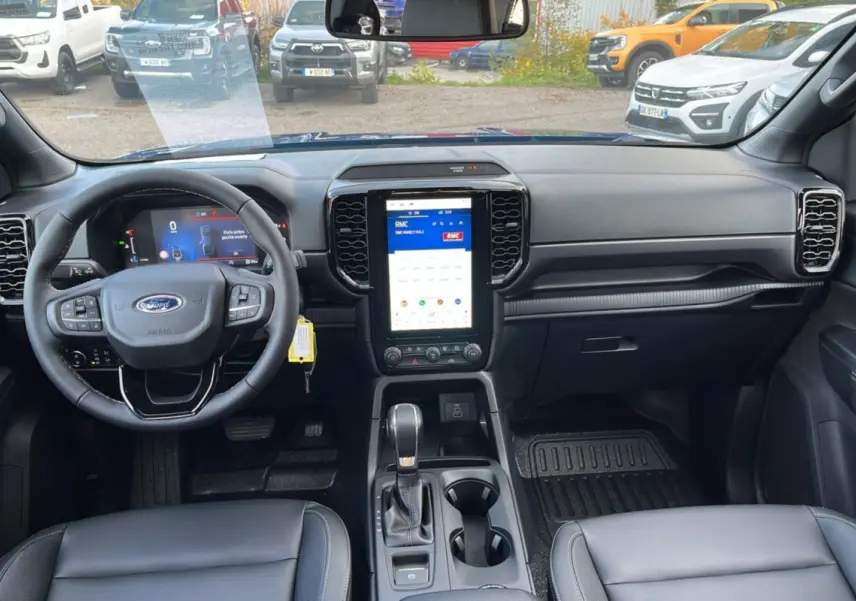 Intérieur du Ford Ranger 2025 vu de face, tableau de bord noir avec écran tactile vertical et volant multifonctions cuir.