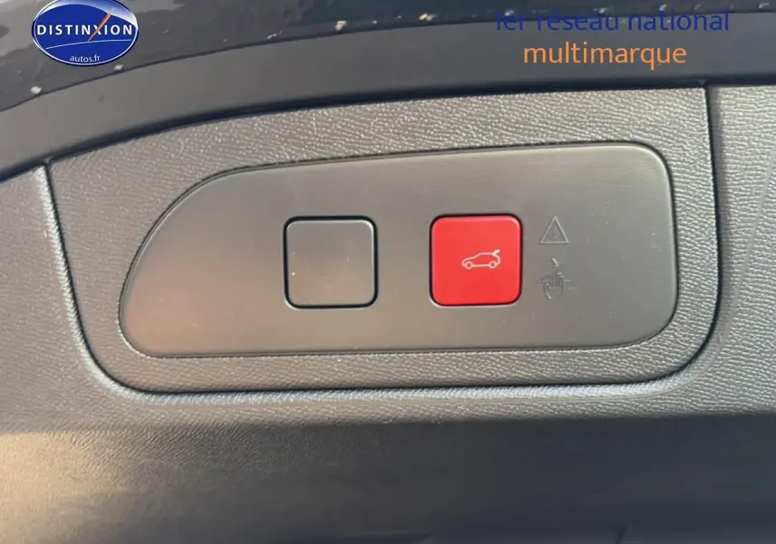 Gros plan sur bouton rouge d'ouverture du coffre dans l'habitacle du DS7 noir 2026, côté conducteur.