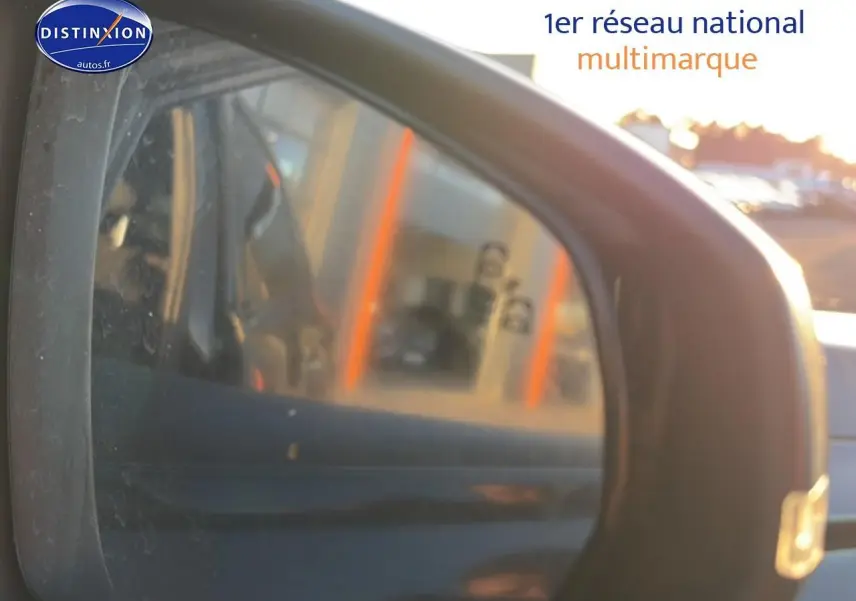 Rétroviseur extérieur droit d'une DS7 noire 2026, reflet flou du côté arrière avec lumière du soleil.