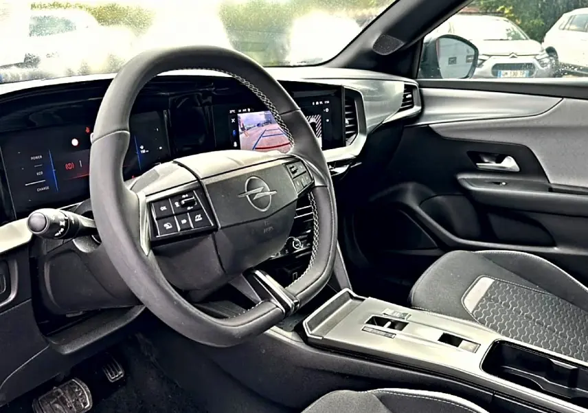 Vue intérieure de l'Opel Mokka 2025 montrant le volant multifonction, l'écran tactile et les sièges gris foncé.