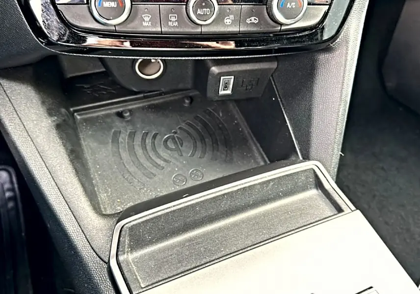 Gros plan sur la console centrale noire de l’Opel Mokka 2025, montrant la zone de recharge sans fil et commandes climatisation.