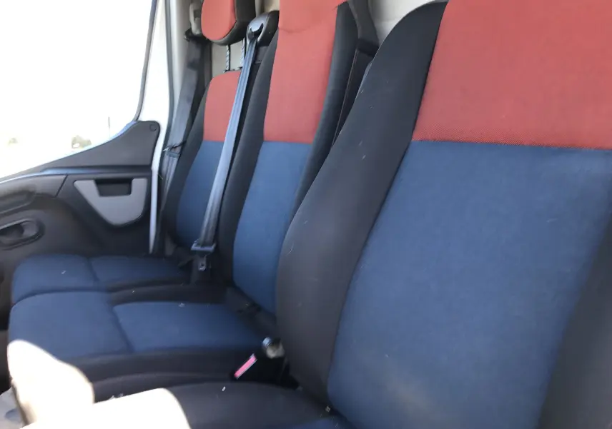 Vue intérieure des sièges avant du Renault Master 2016, tissu bicolore rouge et bleu avec ceintures de sécurité.