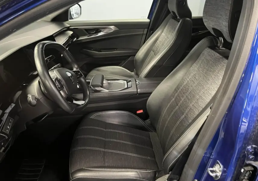 Vue intérieure côté conducteur du Renault Austral bleu 2023 avec sièges mixtes cuir/tissu gris et volant cuir.