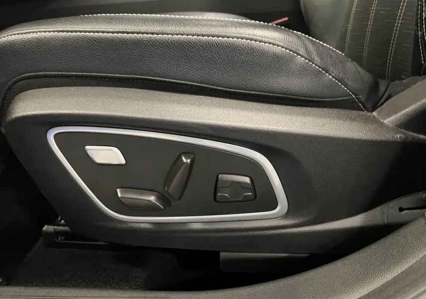 Gros plan sur les commandes électriques du siège conducteur noir avec surpiqûres argent du Renault Austral bleu 2023.