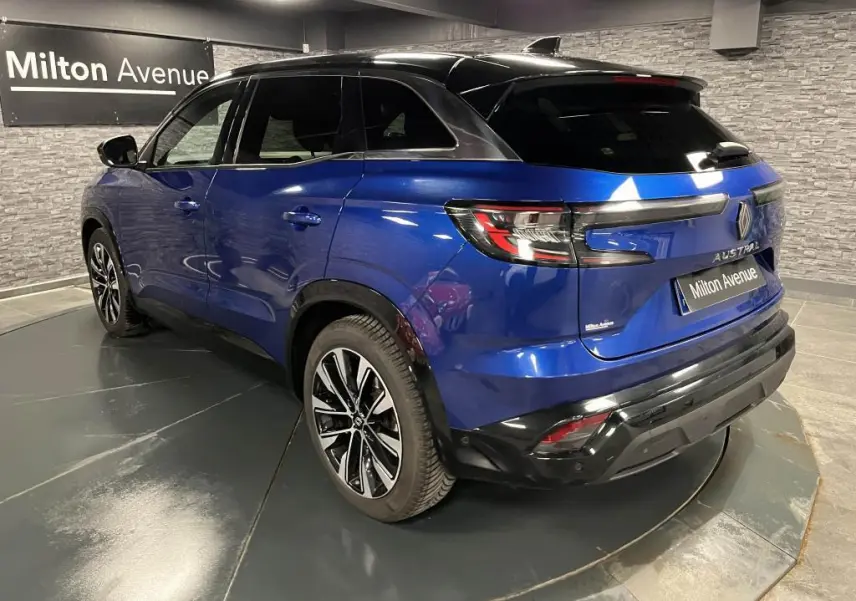 Vue 3/4 arrière droite d'un Renault Austral bleu avec toit noir et jantes alliage noires diamantées.