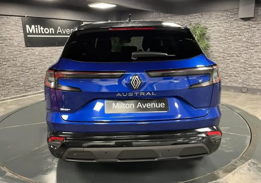 Vue arrière d'un Renault Austral bleu avec hayon motorisé et toit noir étoilé dans un showroom.