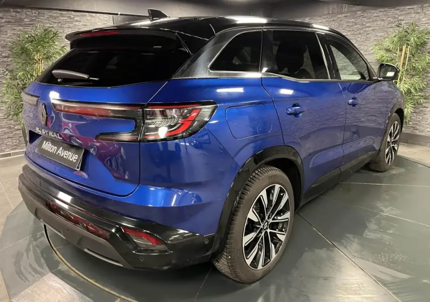 Vue 3/4 arrière droite d'un Renault Austral bleu avec toit noir et jantes alliage noires diamantées.