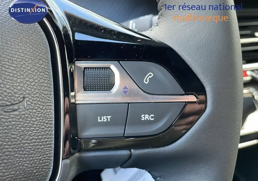 Gros plan sur les commandes multifonctions du volant en cuir noir du Peugeot 2008 gris Artense 2025.