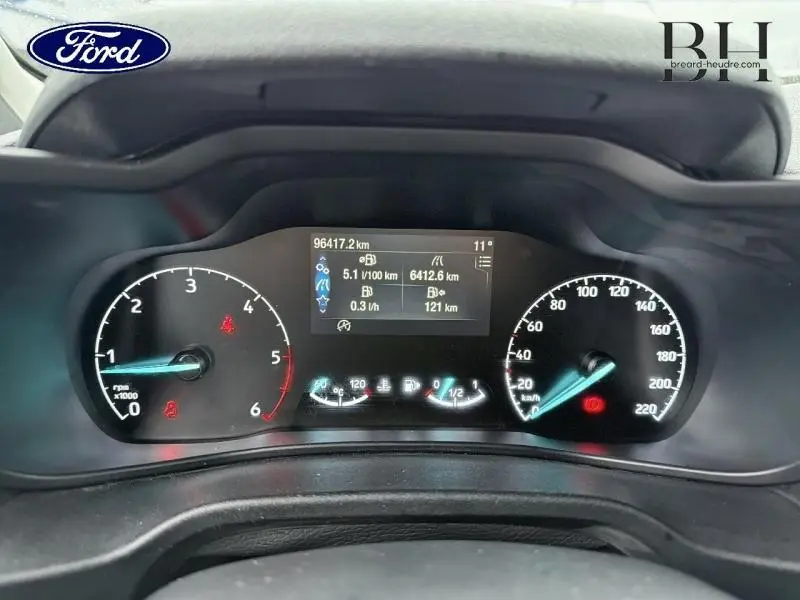 Vue rapprochée du tableau de bord numérique du Ford Transit Connect L1 blanc glacier, affichant compteurs et informations de conduite.