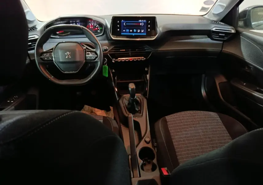 Intérieur de la Peugeot 208 1.2 PT 75 S&S Premium 2022, vue avant centrée sur le tableau de bord et volant noir compact.