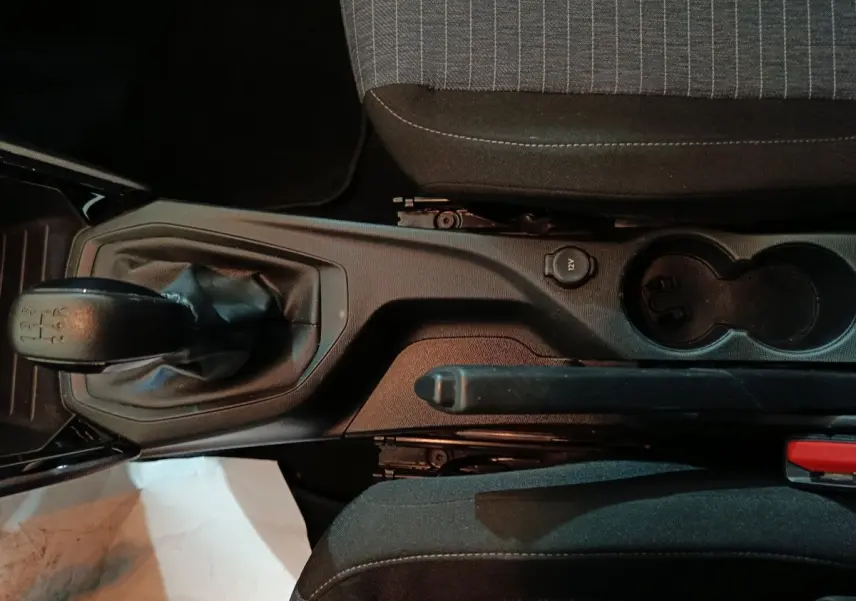 Vue plongeante sur la console centrale d'une Peugeot 208 noire, montrant levier de vitesses manuel et frein à main.