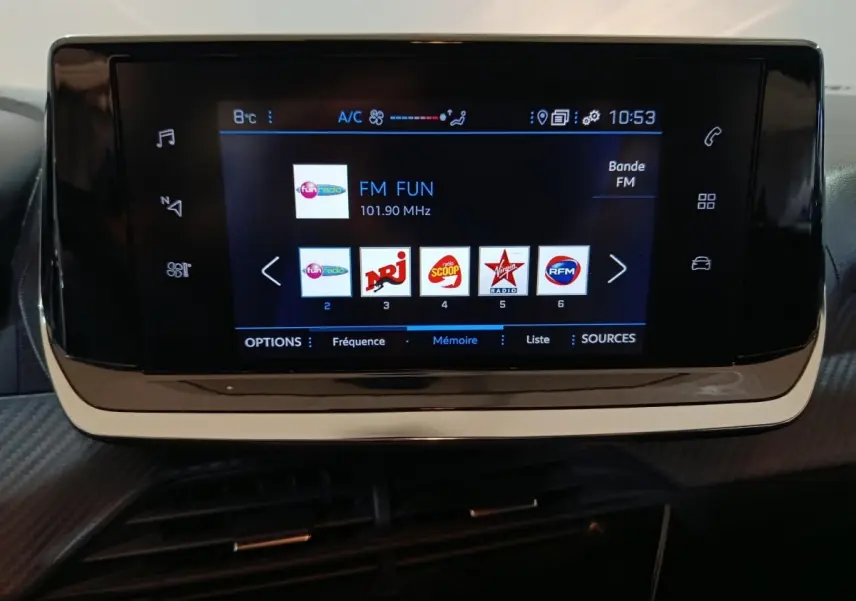 Écran tactile central de la Peugeot 208 2022 affichant les stations radio FM, avec cadre noir brillant.