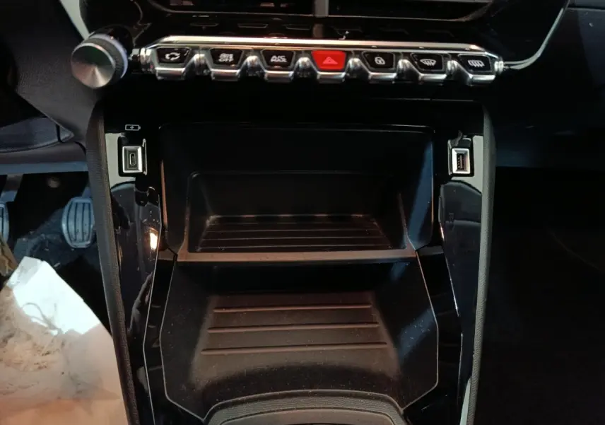 Vue rapprochée de la console centrale noire de la Peugeot 208 1.2 PT 75 S&S Premium avec ports USB et boutons de commande.