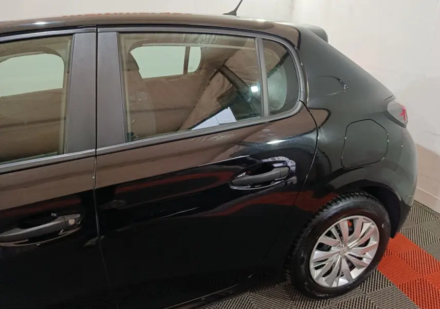 Vue latérale droite sur l'arrière d'une Peugeot 208 noire, mettant en valeur la porte arrière et la roue arrière.