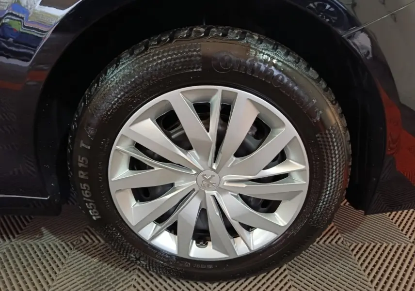 Gros plan sur la roue avant droite d'une Peugeot 208 noire de 2022 avec jante argentée et pneu Continental.