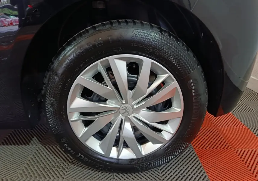 Gros plan sur la roue avant gauche de la Peugeot 208 noire, mettant en valeur la jante argentée au design moderne.