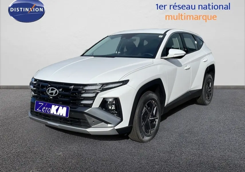 Hyundai Tucson blanc Atlas en 3/4 avant droit, avec calandre noire et jantes bi-ton noires.