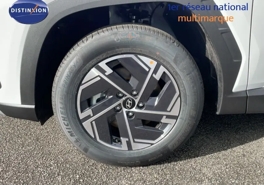 Gros plan sur la roue avant gauche du Hyundai Tucson blanc Atlas avec jante alliage noire et grise.