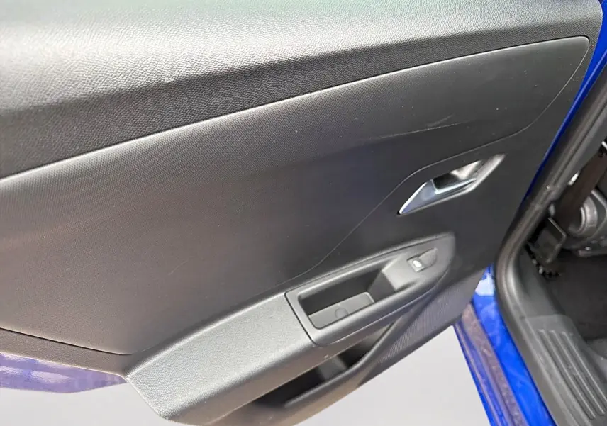 Vue rapprochée de la porte avant gauche noire avec commandes électriques sur un Opel Mokka bleu 2025.