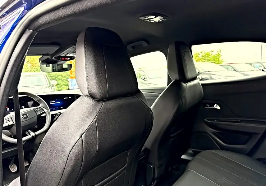 Vue intérieure arrière de l'Opel Mokka bleu 2025, montrant les sièges avant en cuir noir et le tableau de bord digital.