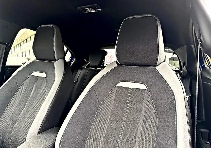 Vue intérieure montrant les sièges avant en tissu gris et noir de l’Opel Mokka 2025, avec appuie-têtes intégrés.