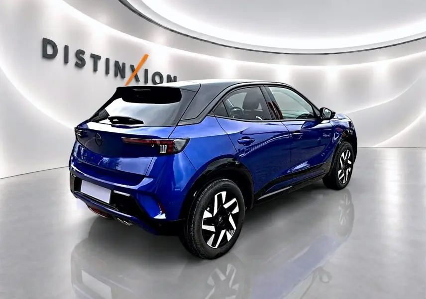 Vue 3/4 arrière droite d'un Opel Mokka bleu avec toit noir, dans un showroom lumineux au sol brillant.