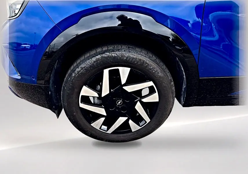 Gros plan sur la roue avant droite d’un Opel Mokka bleu 2025 avec jante noire et argentée au design moderne.
