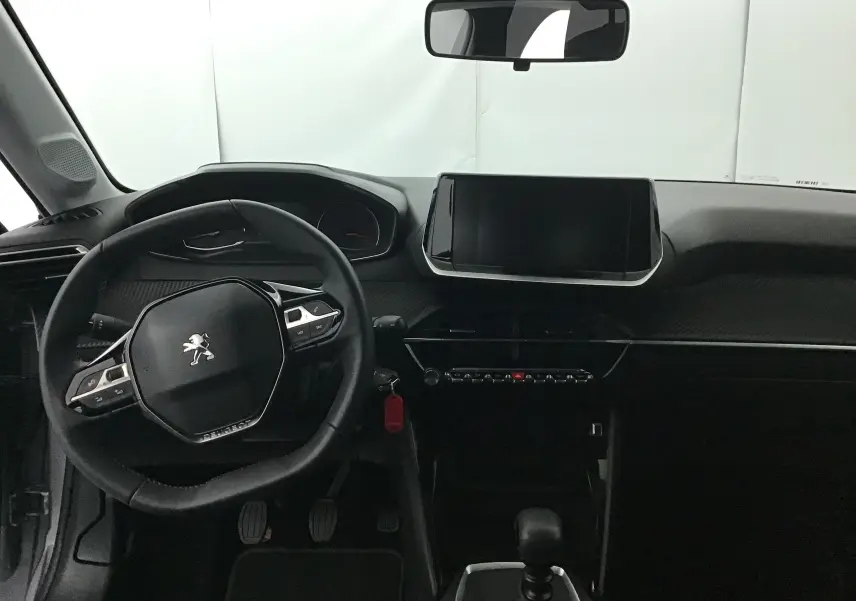 Intérieur de la Peugeot 208 2022, vue frontale du poste de conduite avec volant compact et écran tactile central.