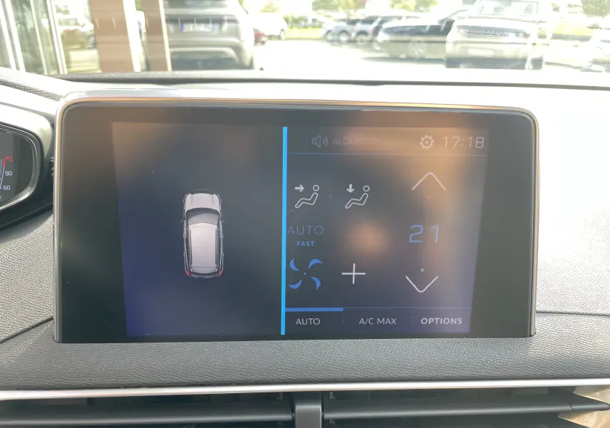 Écran tactile du tableau de bord du Peugeot 3008 blanc de 2018, affichant la climatisation à 21 degrés et la vue du véhicule en haut.