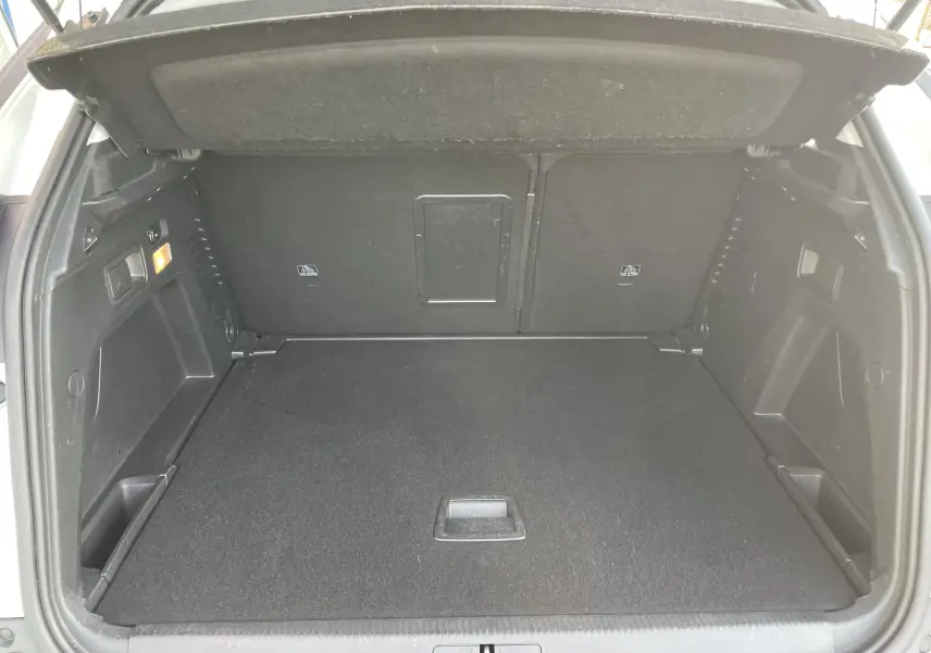 Coffre ouvert du Peugeot 3008 blanc vue de l'arrière, montrant un espace de chargement propre et bien agencé.