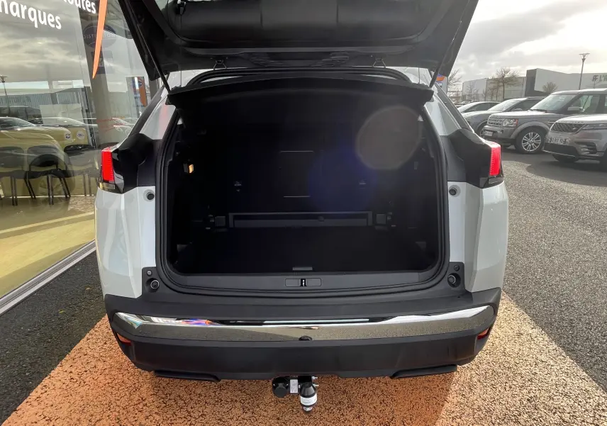 Vue arrière d’un Peugeot 3008 blanc 2018 avec coffre ouvert et attelage visible au centre.