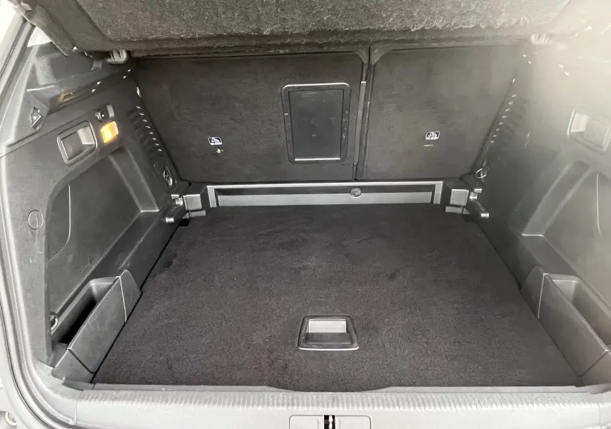 Vue intérieure du coffre spacieux et propre du Peugeot 3008 blanc, avec revêtement noir et éclairage latéral allumé.