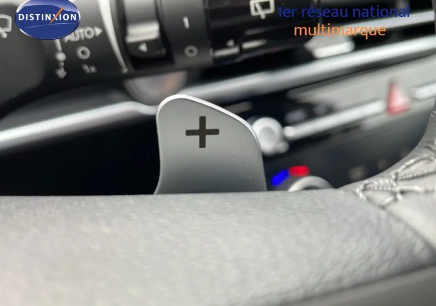 Gros plan sur la palette de changement de vitesse "+" côté droit du volant d'un Hyundai Tucson blanc Atlas, intérieur noir.