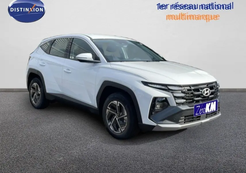 Hyundai Tucson blanc atlas en 3/4 avant droit, avec calandre distinctive et jantes bi-ton modernes.