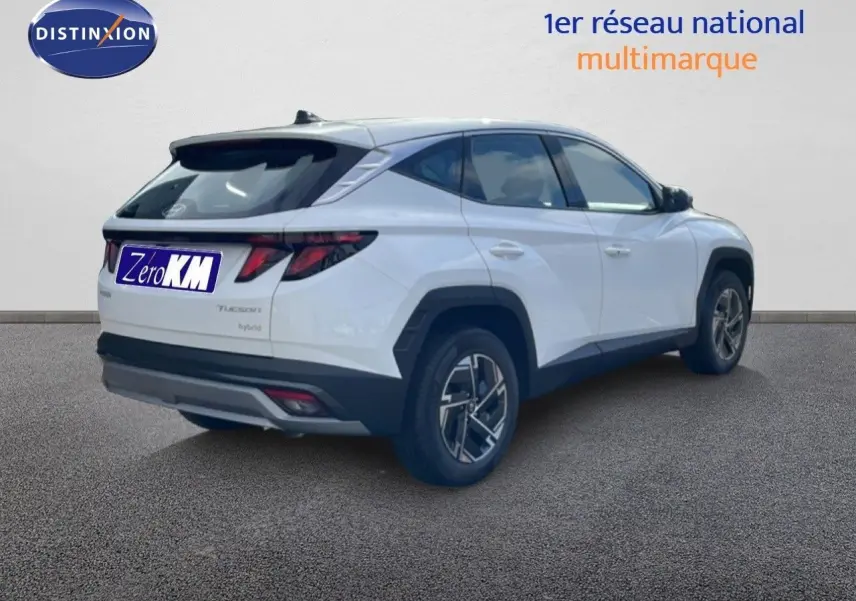 Vue 3/4 arrière droite du Hyundai Tucson blanc Atlas avec jantes bi-ton et feux arrière LED distinctifs.