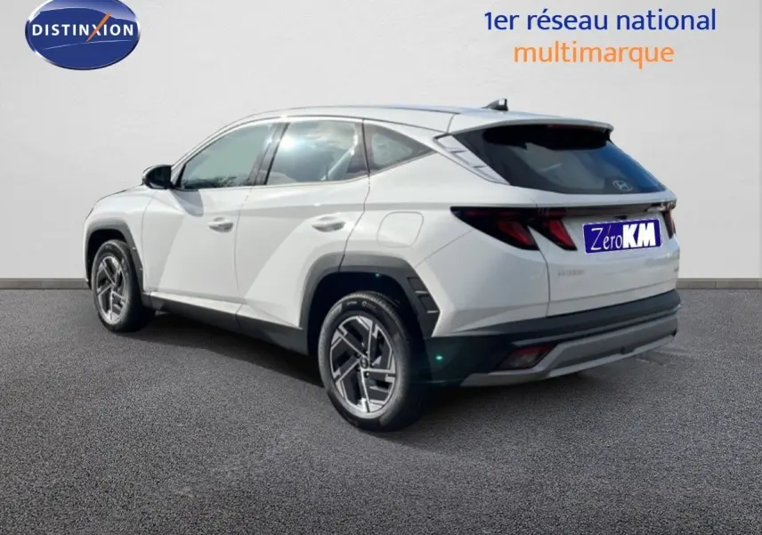 Vue 3/4 arrière droite d'un Hyundai Tucson blanc Atlas 2026 avec jantes bi-ton et vitres teintées.