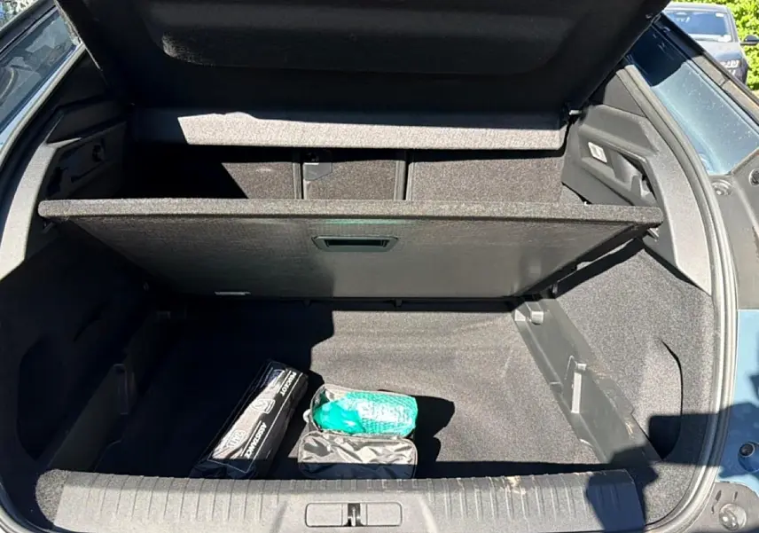 Coffre ouvert du Peugeot 3008 bleu Ingara, vue arrière avec cache-bagages et accessoires de sécurité visibles.