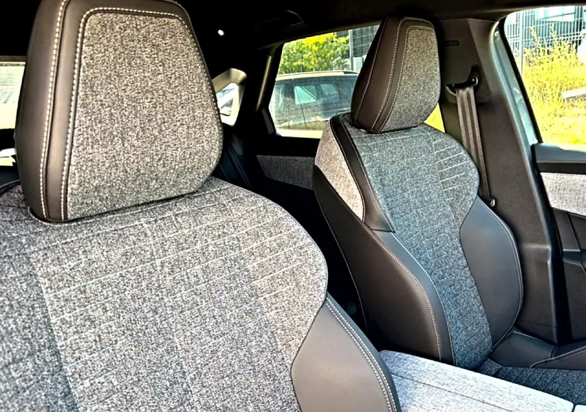 Gros plan sur les sièges avant tissu gris et cuir noir du Peugeot 3008 1.2 Hybrid 145 Allure 2025, côté conducteur et passager.