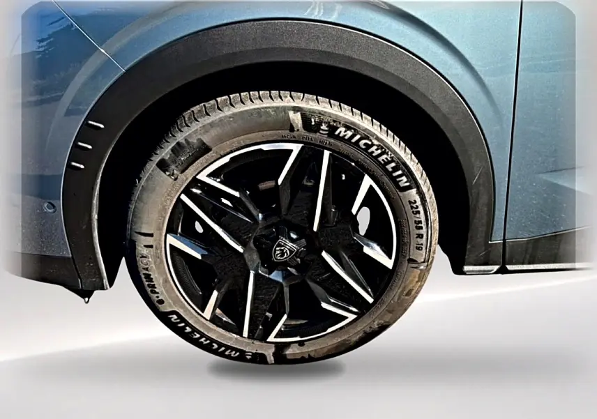 Gros plan sur la roue avant gauche du Peugeot 3008 bleu Ingara avec jante alu noire et détails Michelin visibles.