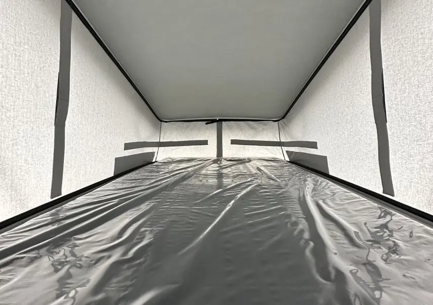 Intérieur du toit relevable du Citroën Jumpy van blanc, montrant la couchette et la toile de protection.