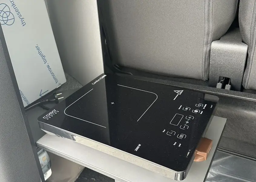 Réchaud électrique noir sur tablette coulissante à l'intérieur arrière d'un Citroën Jumpy van blanc.