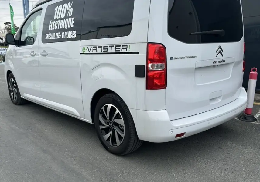 Vue 3/4 arrière droite d'un Citroën Jumpy van blanc électrique avec marquage "100% électrique" et jantes alu 17 pouces.