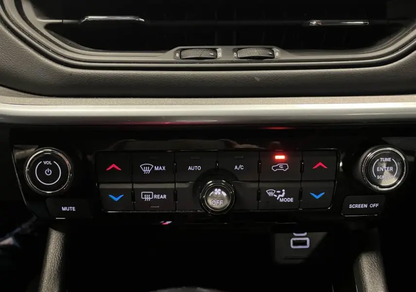 Panneau de commande de climatisation et audio du Jeep Compass 2024, avec boutons rétroéclairés et finition noire brillante.