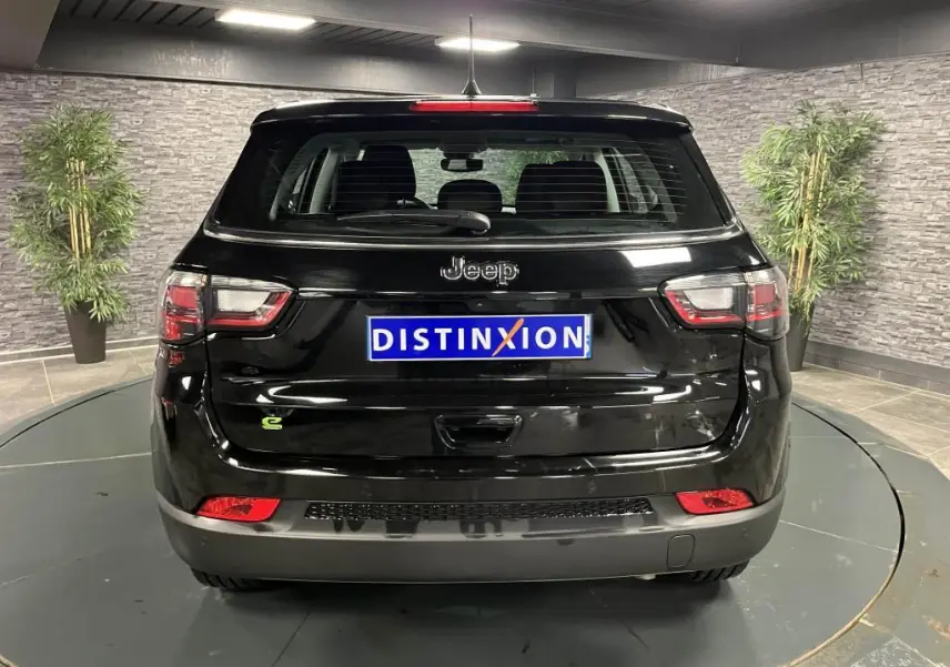 Vue arrière d'un Jeep Compass noir 2024 avec logo Jeep et feux arrière LED dans un showroom.